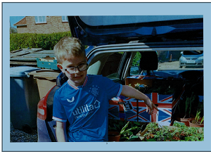 Rupert Meechan pointing at a car boot containing plants he's grown Photo small